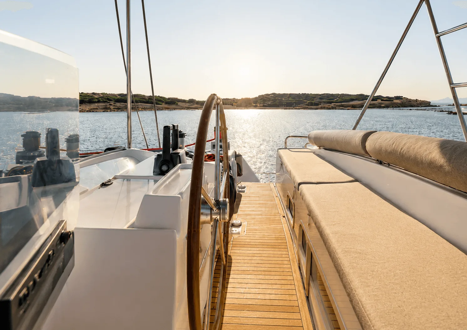 The wheel and helm station of a sailing catamaran, looking out over a calm bay