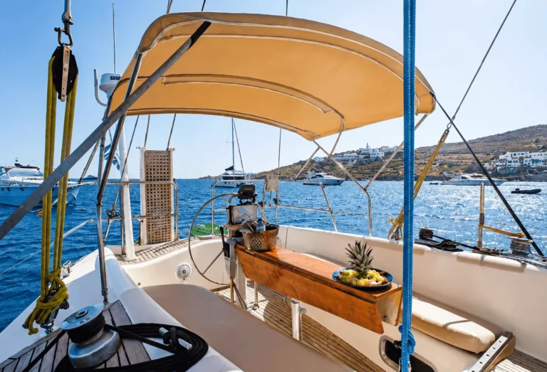 The cockpit of a sailing yacht with a winch and lines under a bimini, off a Greek island