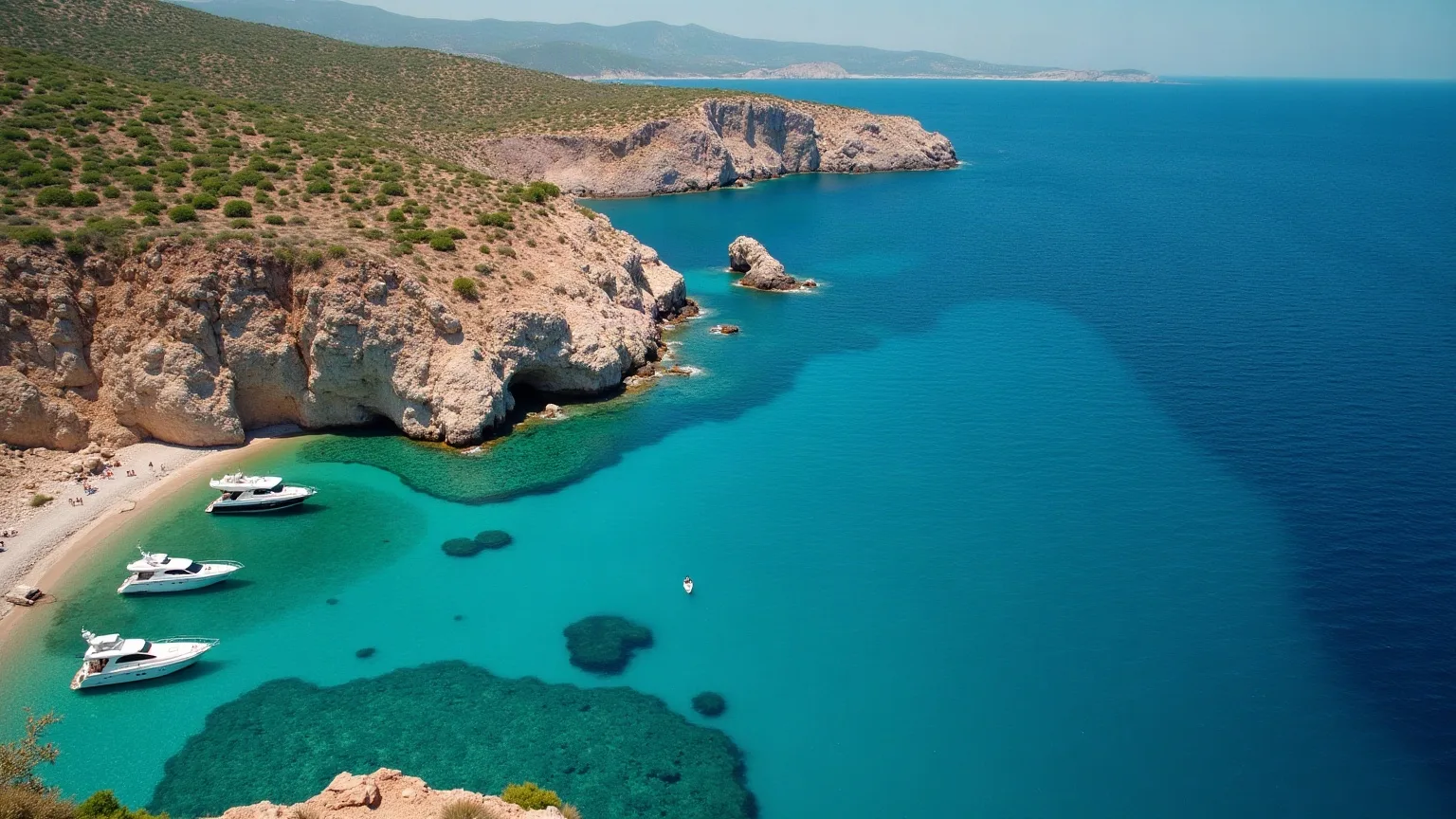 Yachts at anchor in a sheltered turquoise bay below a rocky headland